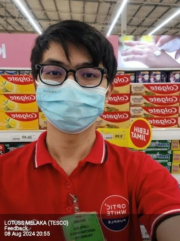 Tan in a red Colgate Optic White promoter shirt in front of a Colgate shelf display.