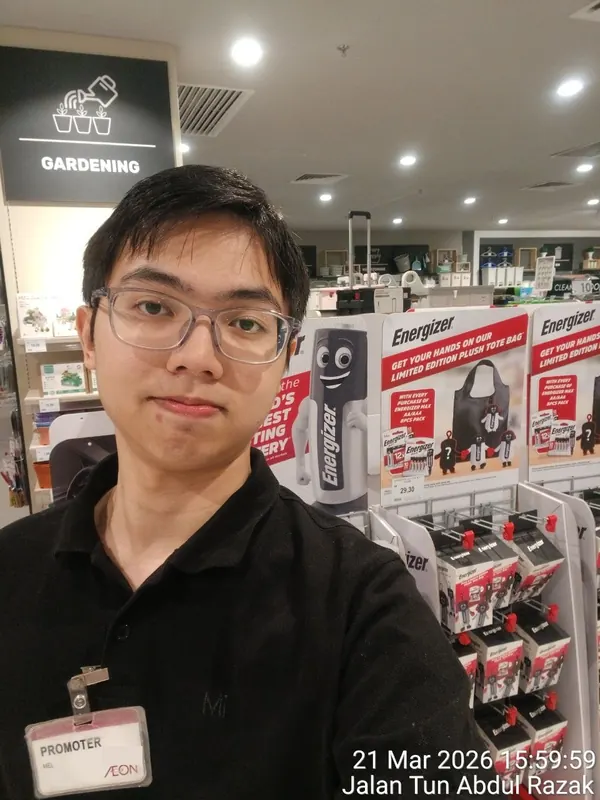 Tan in an AEON promoter uniform beside an Energizer battery display.